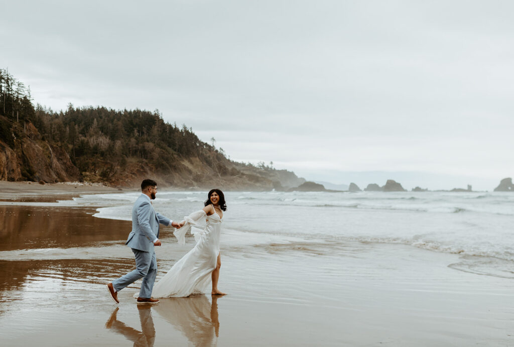 bride and groom running on the beach at Ecola State Park